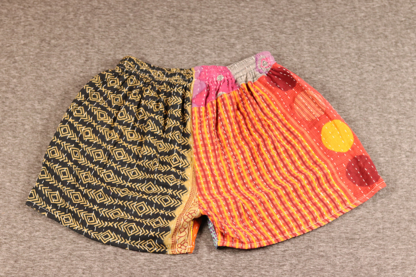 Unisex Kantha shorts with black and orange cotton panels featuring geometric and abstract patterns, detailed with Kantha stitching and drawstring waist.”