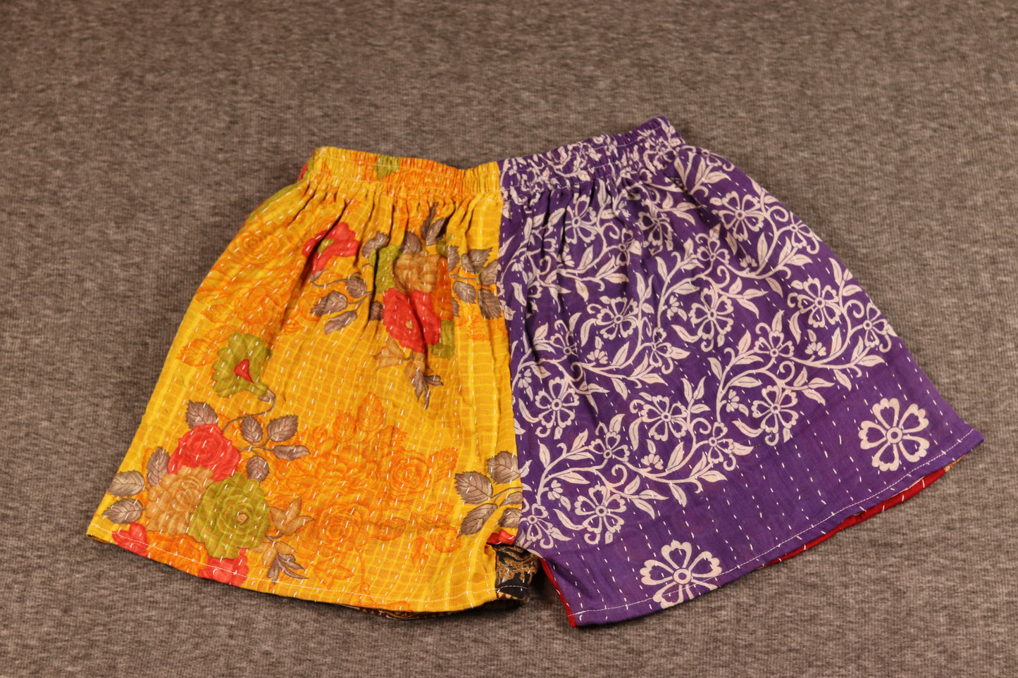 Unisex Kantha shorts with yellow and purple cotton panels featuring floral prints, detailed with Kantha stitching and a drawstring waist.