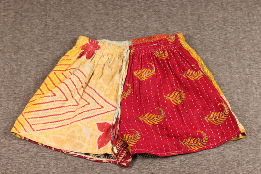 Unisex Kantha shorts with golden yellow and crimson cotton panels featuring chevron and leaf prints, detailed with Kantha stitching and a drawstring waist.