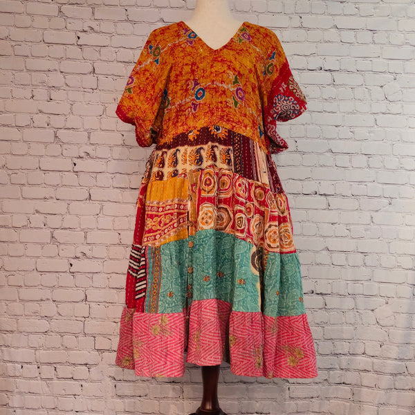 Twillow Saffron Sky Kantha Midi Dress featuring a bright orange floral bodice and colorful patchwork skirt with Kantha stitching detail.