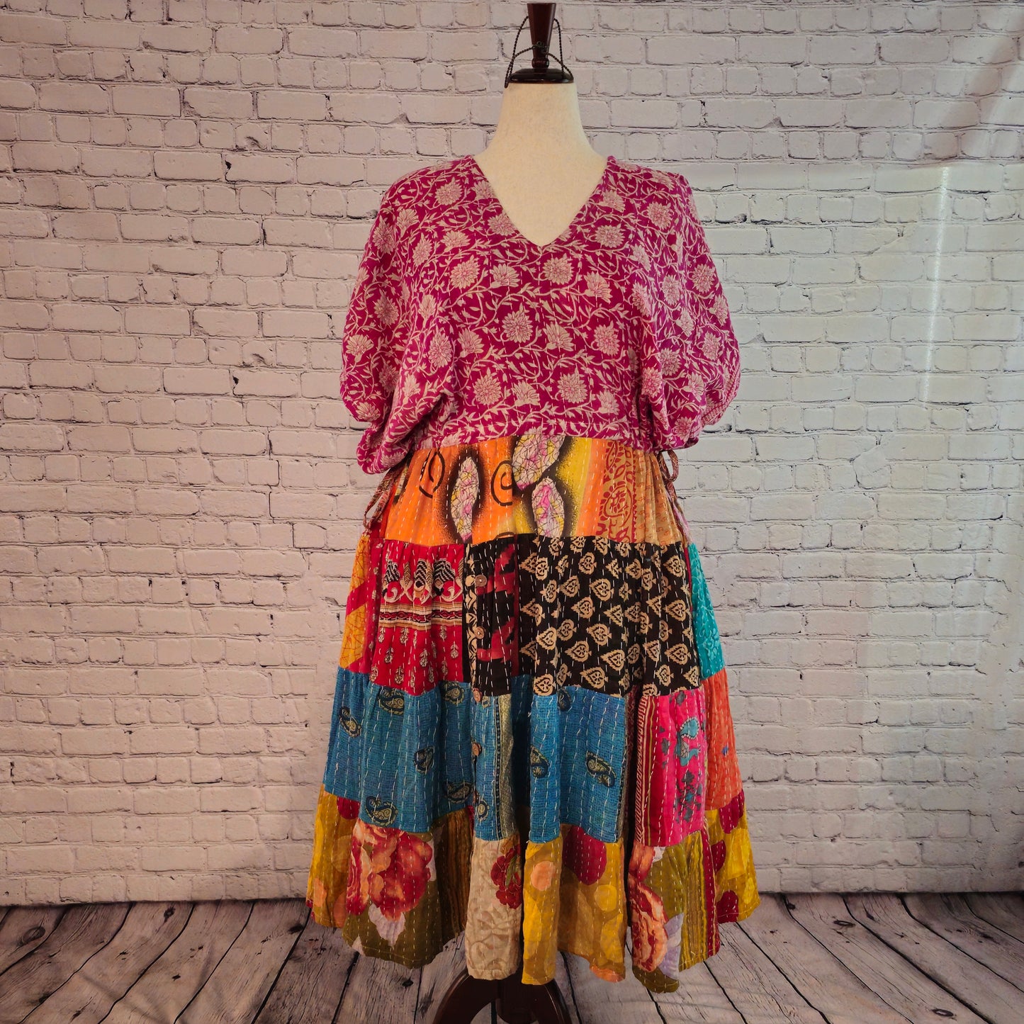 Twillow Sunset Bloom Kantha Midi Dress featuring magenta floral bodice and warm orange, turquoise, and gold patchwork skirt with Kantha stitching.
