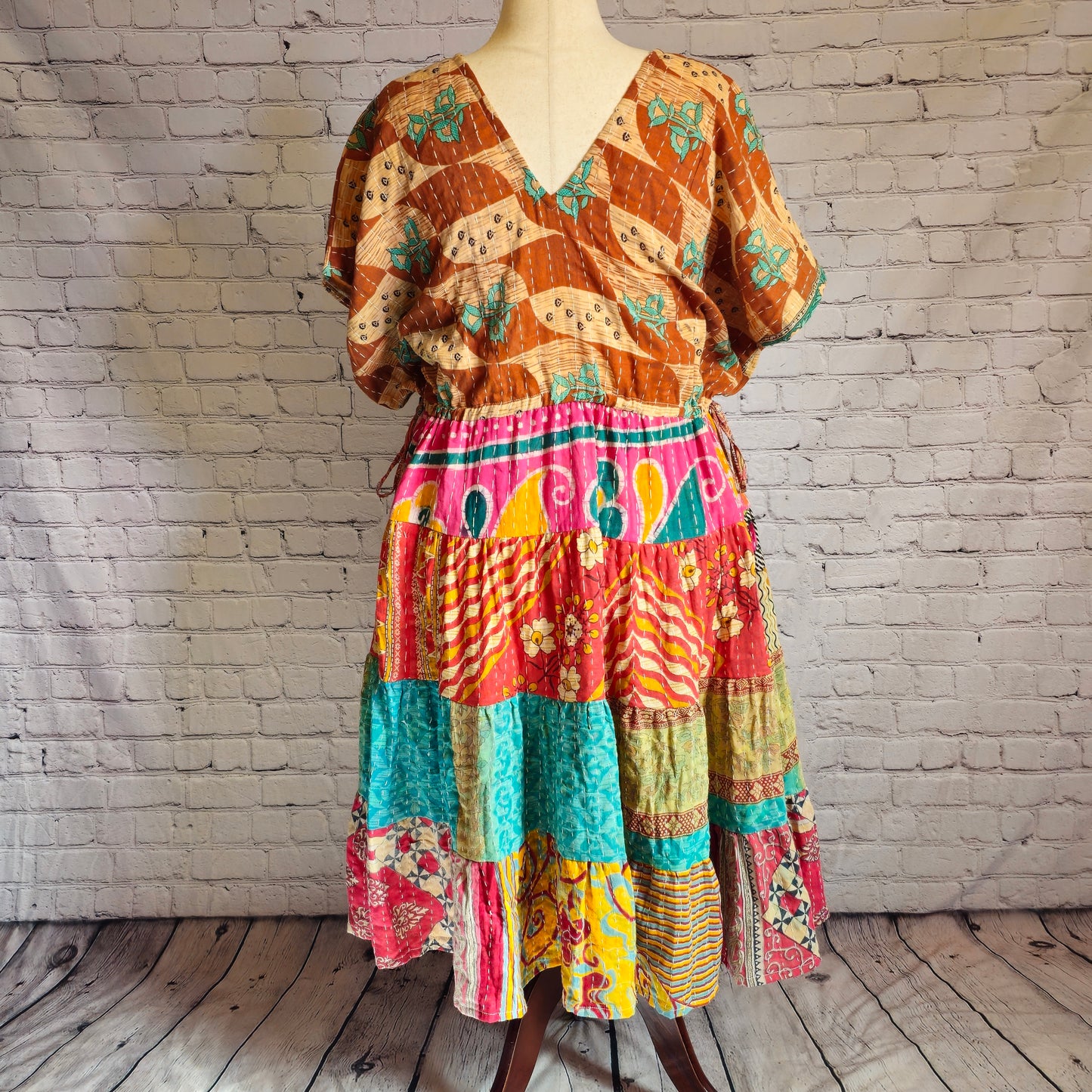 Twillow Nomad Spirit Kantha Midi Dress featuring a golden-brown top with turquoise patterns and a colorful patchwork skirt in coral, teal, and gold.