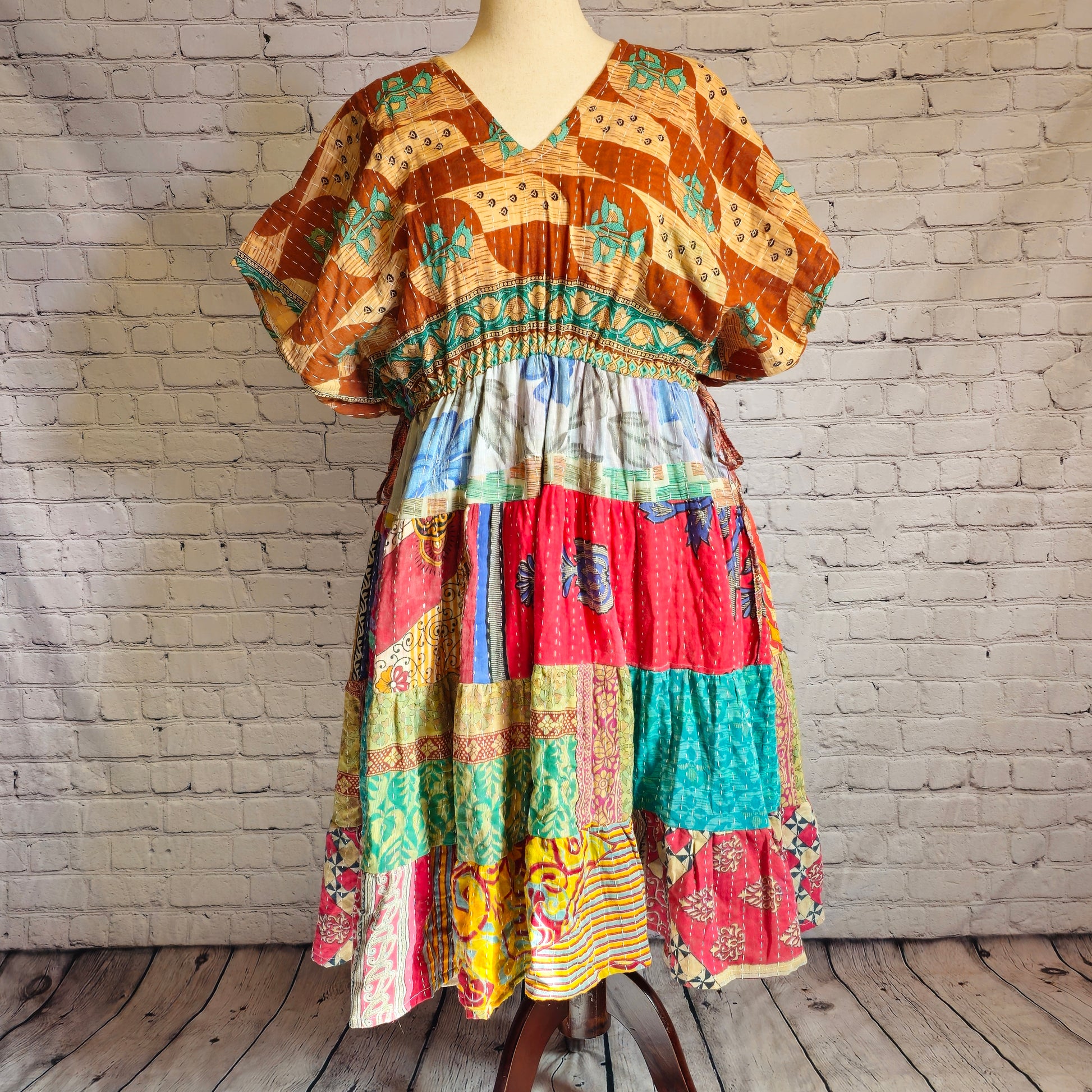 Twillow Nomad Spirit Kantha Midi Dress featuring a golden-brown top with turquoise patterns and a colorful patchwork skirt in coral, teal, and gold.