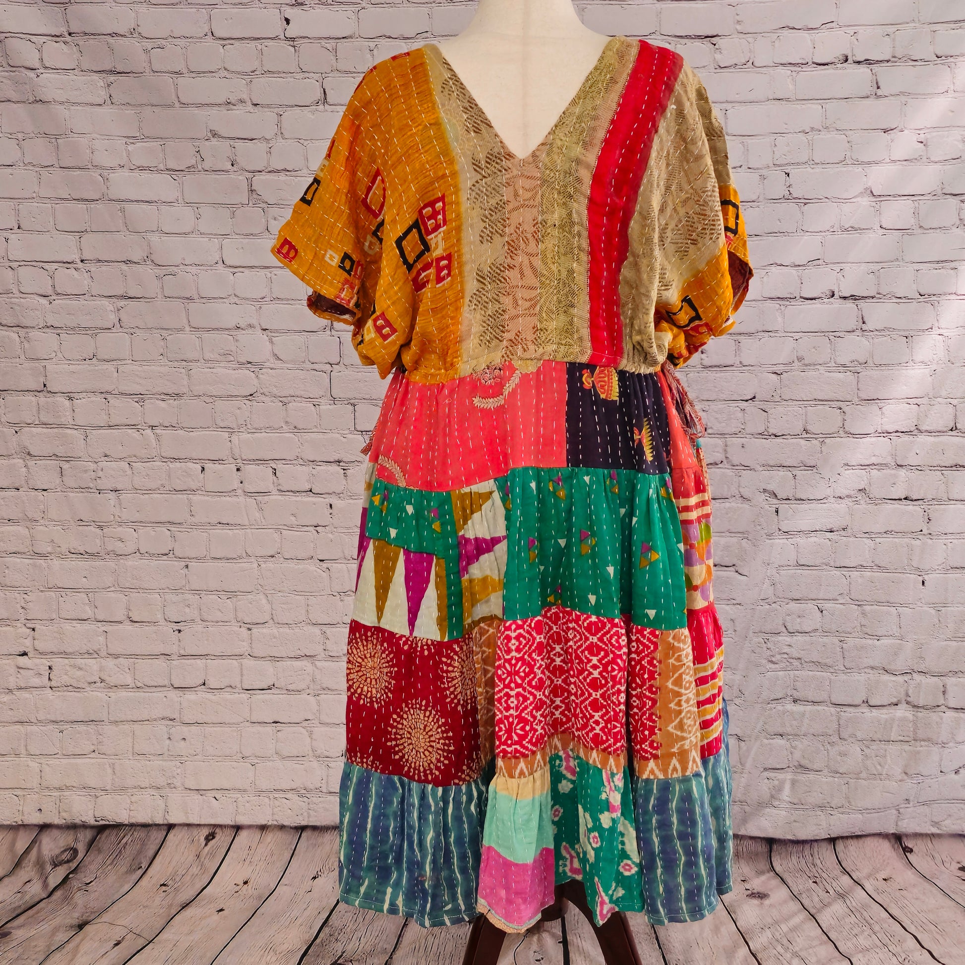 Twillow Sundara Glow Kantha Midi Dress featuring a golden-brown bodice and vivid coral, teal, and red patchwork skirt accented with Kantha stitching.