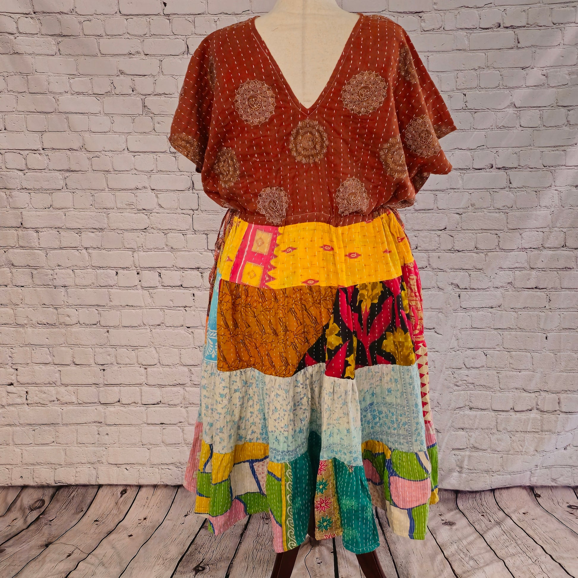 Twillow Terra Sol Kantha Midi Dress featuring a brown patterned bodice and patchwork skirt with orange, aqua, yellow, and pink panels accented by Kantha stitching.