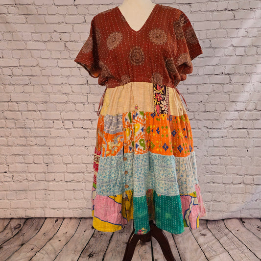 Twillow Terra Sol Kantha Midi Dress featuring a brown patterned bodice and patchwork skirt with orange, aqua, yellow, and pink panels accented by Kantha stitching.
