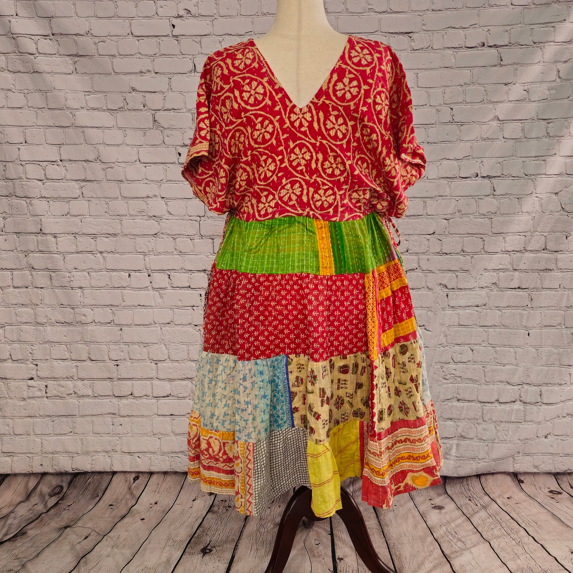 Twillow Solstice Garden Kantha Midi Dress with a red floral bodice and green, blue, and coral patchwork skirt accented by Kantha stitching.
