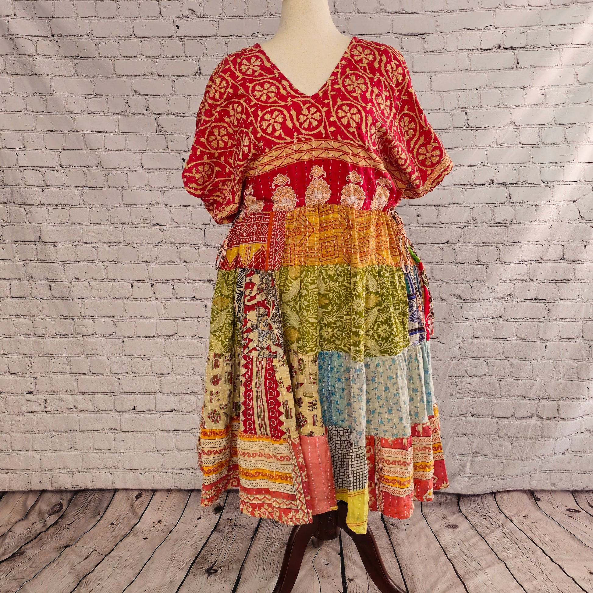 Twillow Solstice Garden Kantha Midi Dress with a red floral bodice and green, blue, and coral patchwork skirt accented by Kantha stitching.