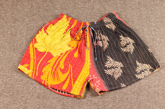 Unisex Kantha patchwork shorts with red and yellow leaf prints and black palm patterns, made from reclaimed cotton sari fabric with handsewn Kantha stitching.