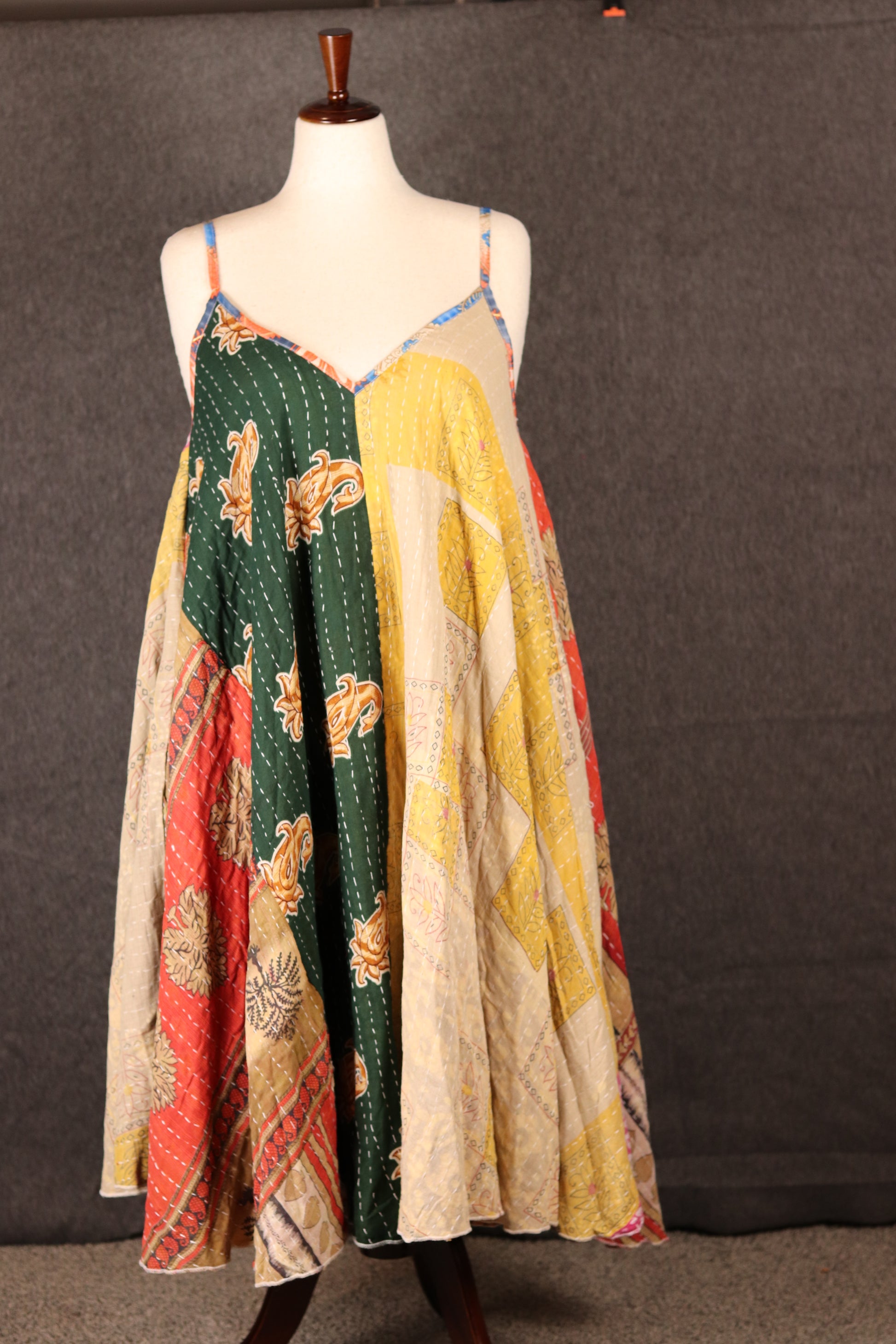 Front-facing image of Sora Kantha patchwork dress on mannequin, recycled sari fabric with hand-stitched Kantha embroidery.
