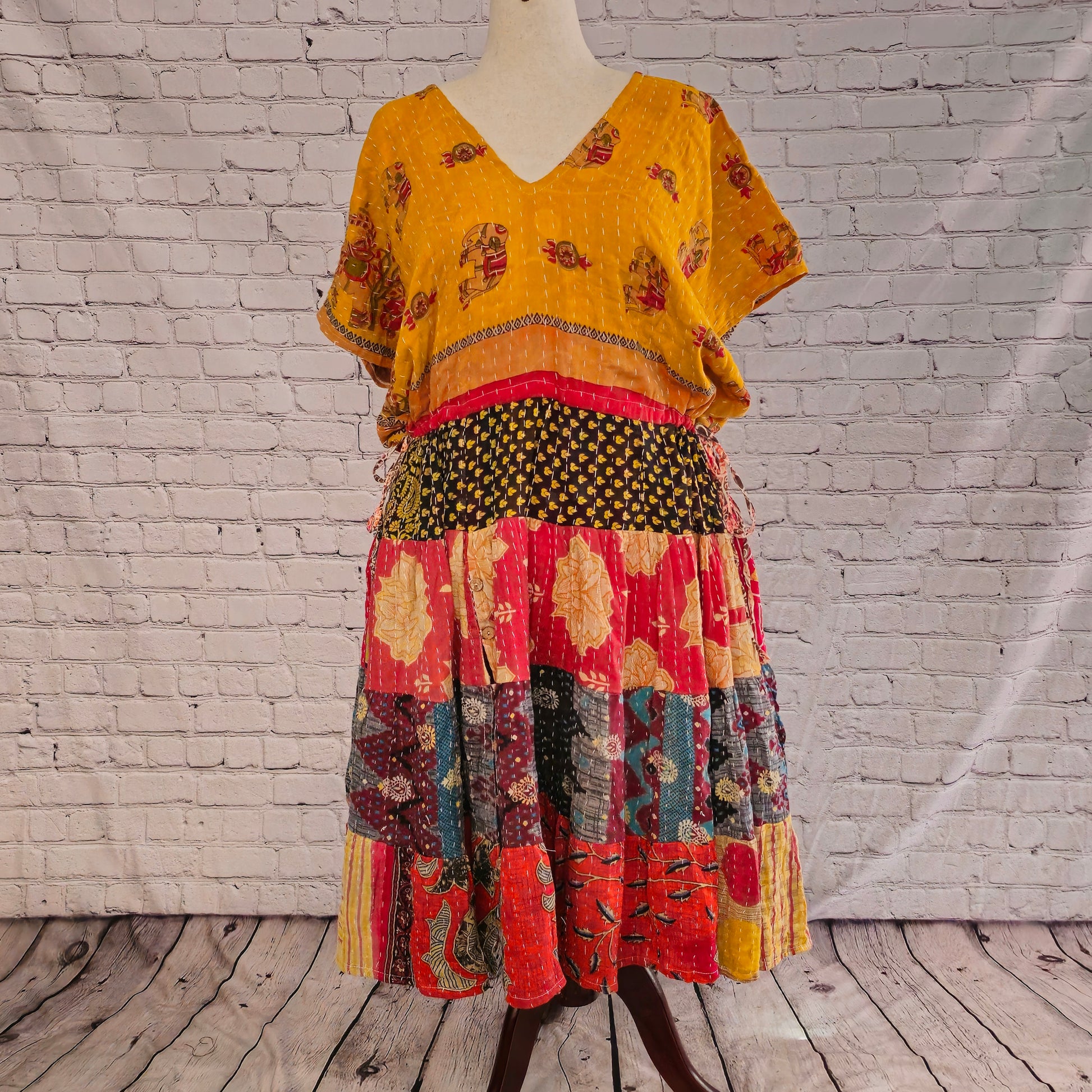 Twillow Desert Marigold Kantha Midi Dress featuring a golden yellow bodice and colorful red, teal, and black patchwork skirt with Kantha stitching detail.