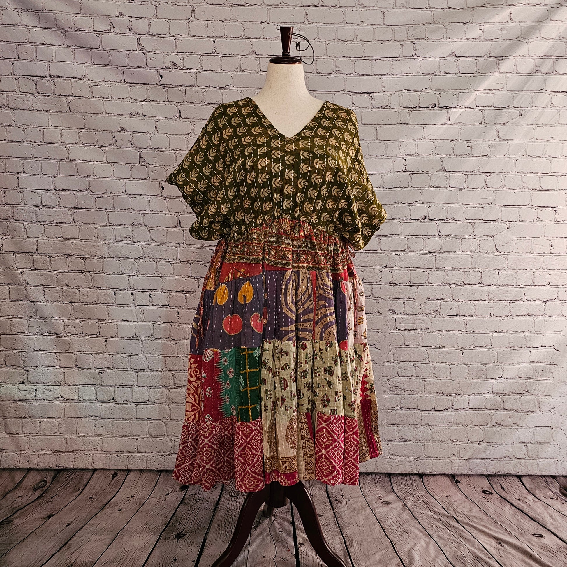 Twillow Forest Whimsy Kantha Midi Dress featuring an olive leaf-print top and a multi-color patchwork skirt in plum, sage, red, and gold accented by Kantha stitching.