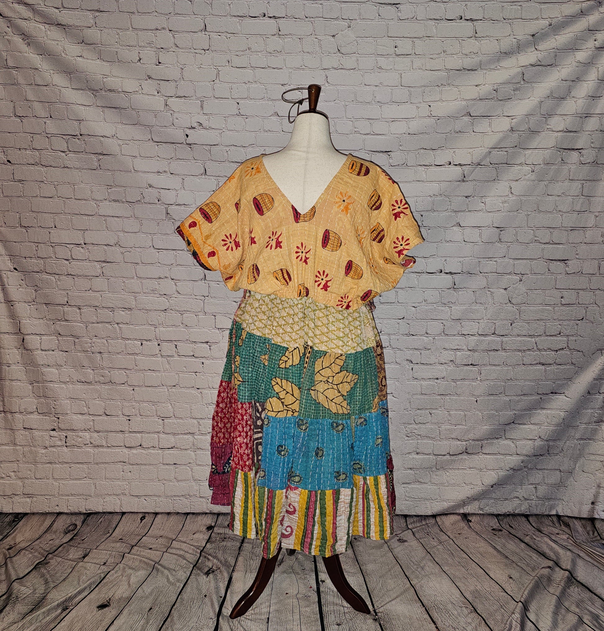 Twillow Sunlit Bazaar Kantha Midi Dress with a sandy gold patterned top and a colorful blue, green, and multicolor patchwork skirt enhanced by Kantha stitching.