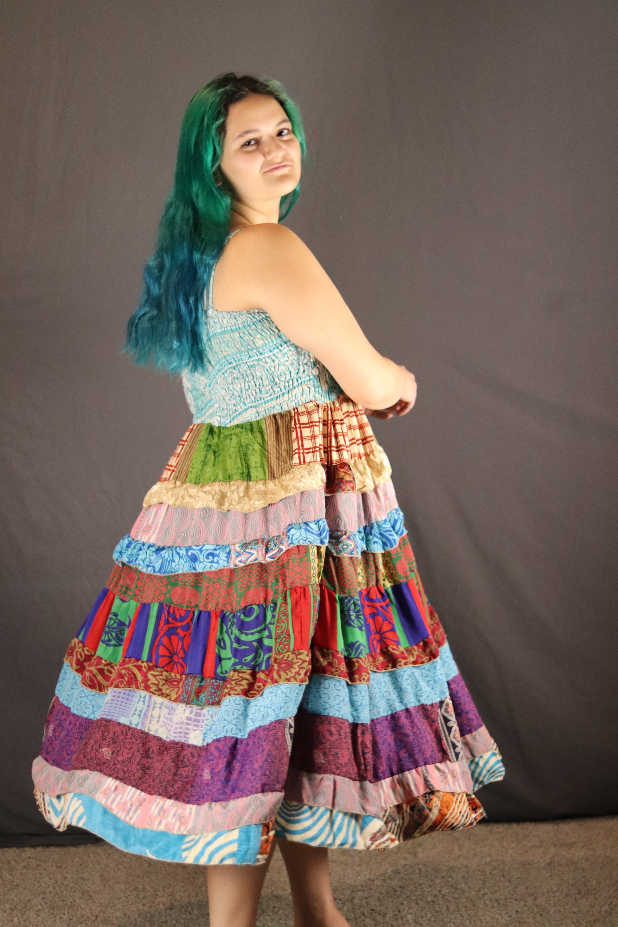 Person wearing a colorful, patterned recycled sari dress on a plain background
