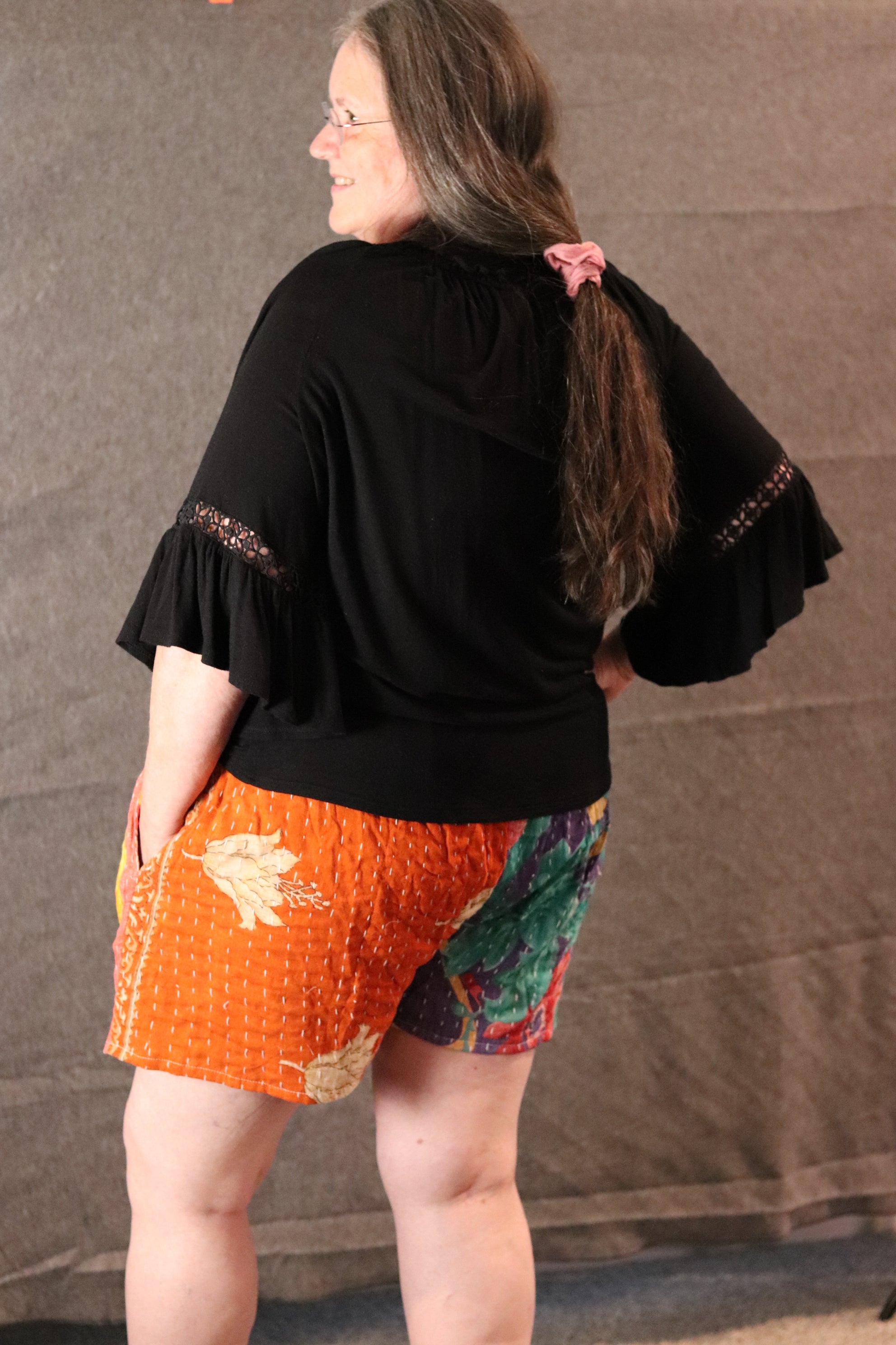 Person with their hand in their pocket wearing multicolored kantha shorts