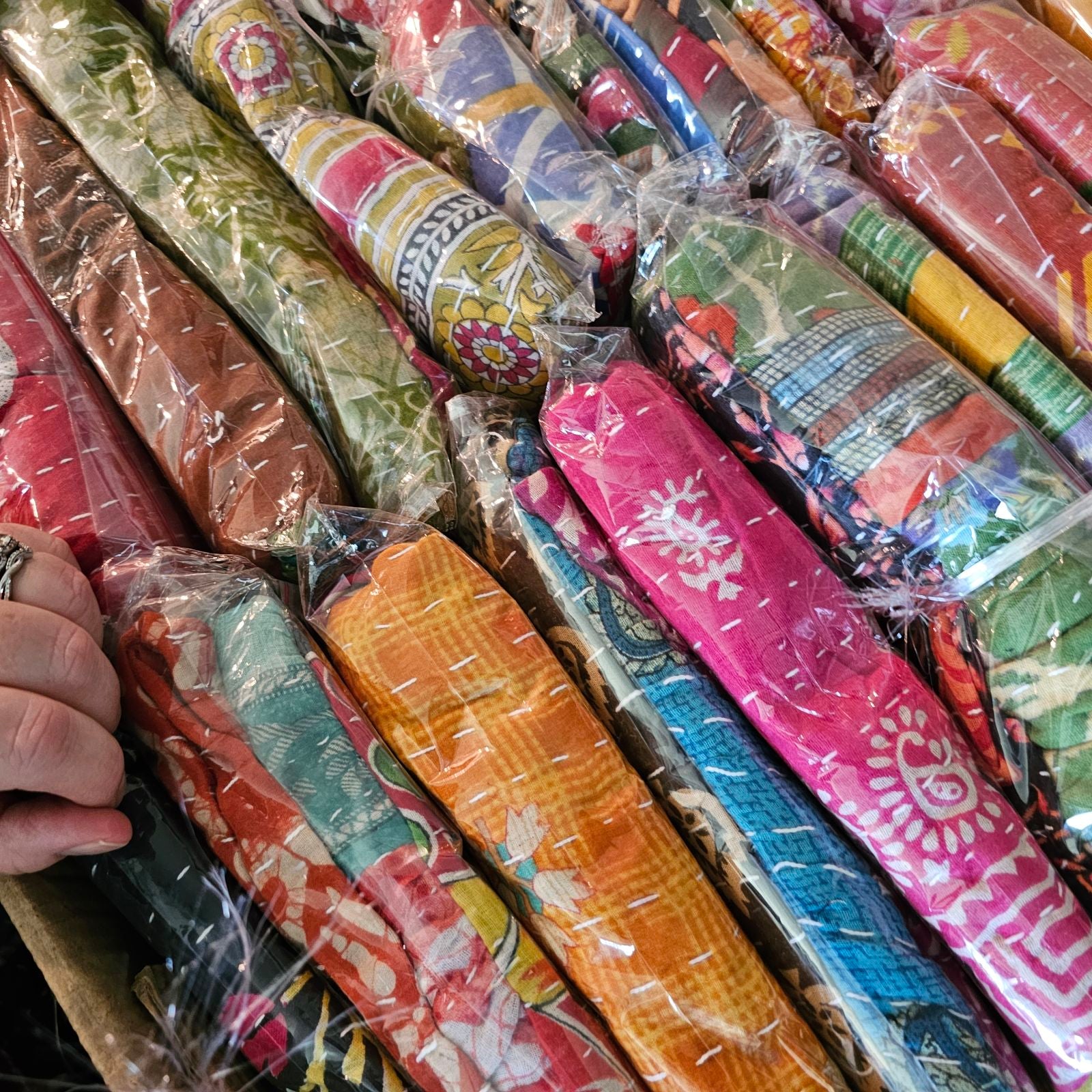 Colorful fabric rolls in various patterns and colors, some with visible branding, arranged in a row.