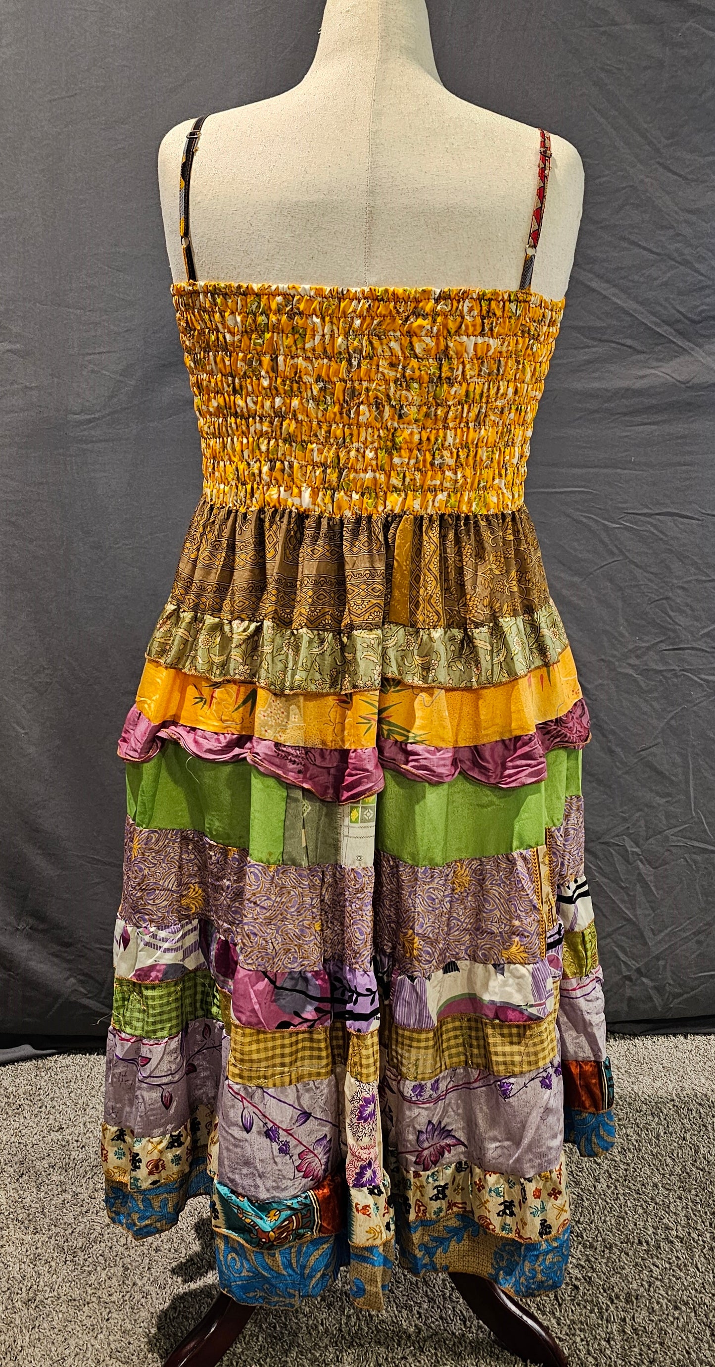 Meadowlark boho patchwork tiered dress in golden yellow, olive green, and violet tones with smocked bodice and flowy silhouette.