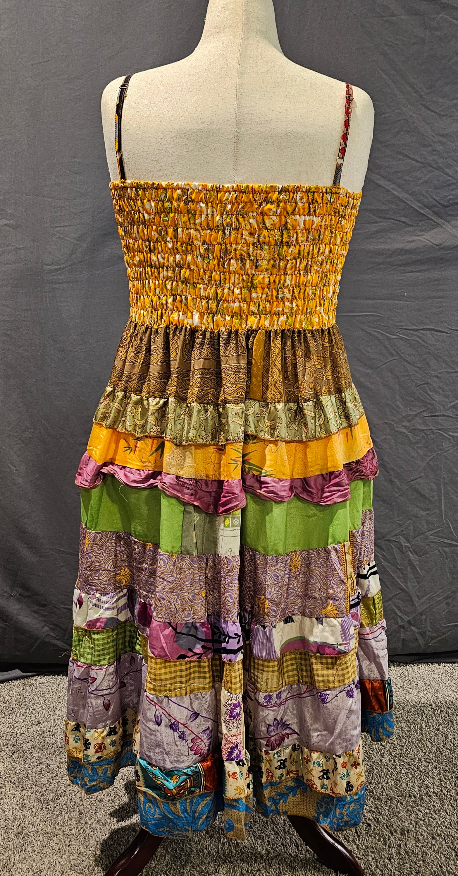 Meadowlark boho patchwork tiered dress in golden yellow, olive green, and violet tones with smocked bodice and flowy silhouette.