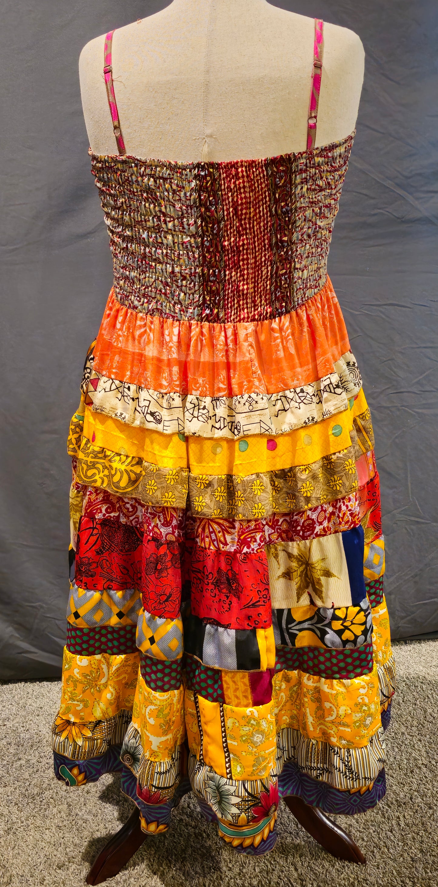 Bohemian patchwork dress with orange and yellow tiered skirt and smocked top.