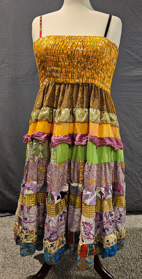 Meadowlark boho patchwork tiered dress in golden yellow, olive green, and violet tones with smocked bodice and flowy silhouette.